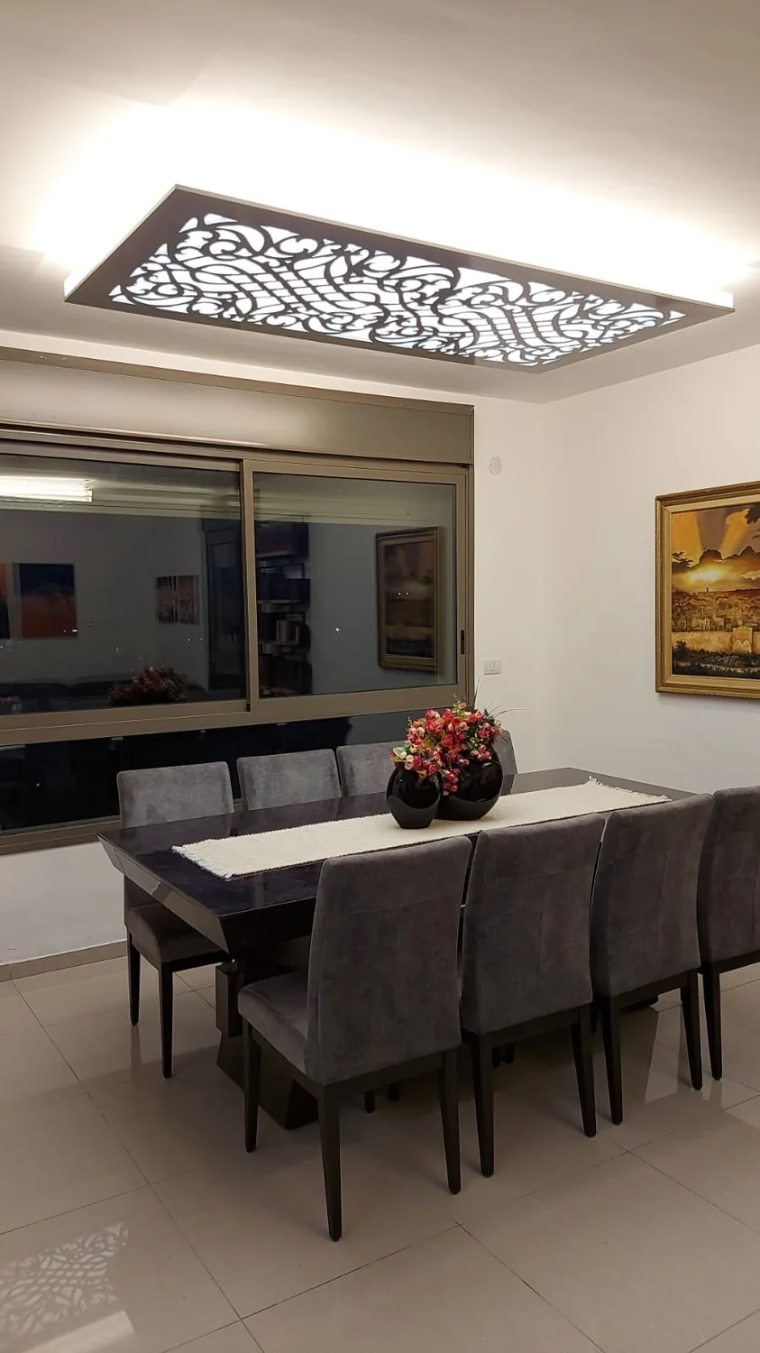 תקרה מונמכת עם פאנל מגזרת עיטורים מסולסלים מעל שולחן אוכל