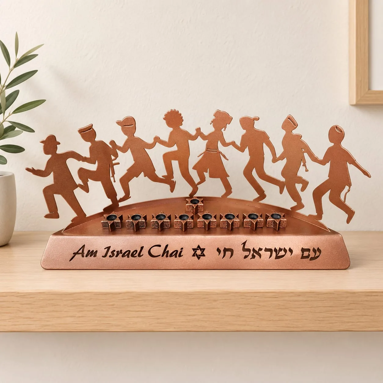 חנוכיית אחדות: שורת דמויות רוקדות חתוכות בנחושת מעל בסיס עם הכיתוב עם ישראל חי